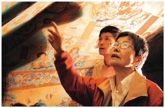 ▲樊錦詩（右一）在莫高窟第八十五窟壁畫修復(fù)現(xiàn)場(chǎng)。（敦煌研究院供圖）